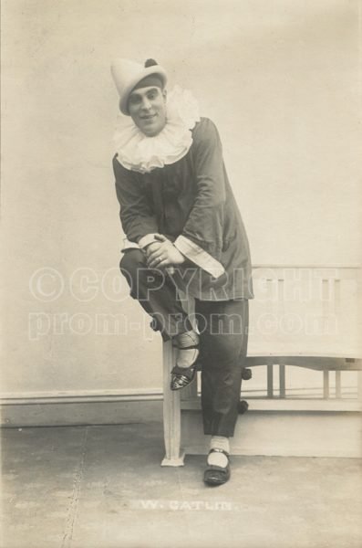 Will Catlin in dark pierrot costume perched on bench